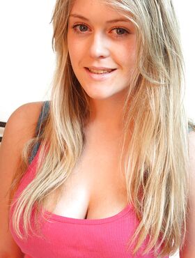 Petite blonde teen posing on the bed and uncovering her big tits