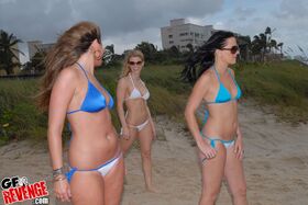 3 bikini clad females walk around the beach and boardwalk in sunglasses