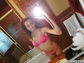 Curly-haired latina slipping off her pink lingerie and making selfies