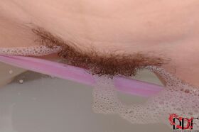 Natural redhead Denisa plunges her hairy vagina into a bathtub full of water