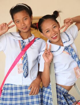 Young Asian schoolgirls lift their uniform skirts to show tiny bare pussy