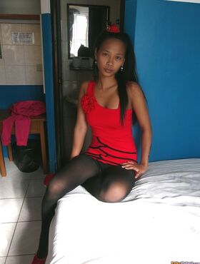 Slim Asian teen Trisha Mae doffs her red dress and flaunts her pussy on a bed