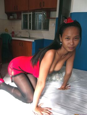 Slim Asian teen Trisha Mae doffs her red dress and flaunts her pussy on a bed