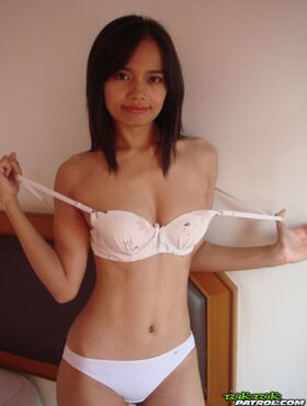 Petite girl from Thailand does a slow striptease on top of a motel bed