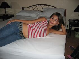 Pinay bargirl takes off a shirt to pose in a strapless bra and jeans on a bed