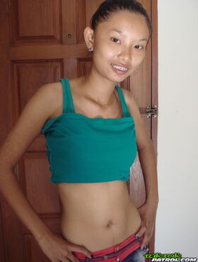 Fragile Thai girl takes her panties off and stays naked in doorway