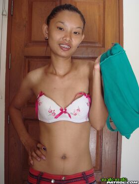 Fragile Thai girl takes her panties off and stays naked in doorway