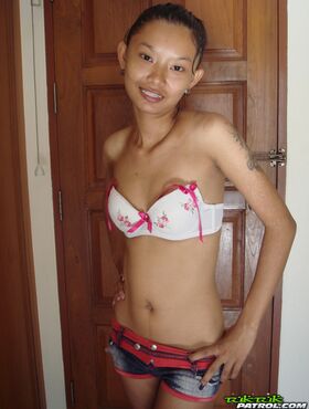 Fragile Thai girl takes her panties off and stays naked in doorway