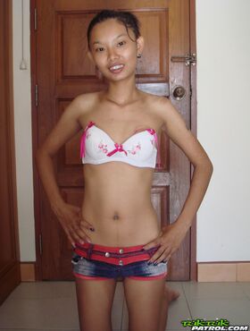 Fragile Thai girl takes her panties off and stays naked in doorway