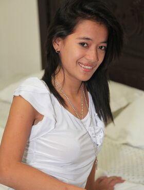 Filipina girl wears a nice smile while making her nude posing debut on a bed