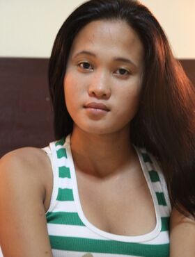 Young Filipina girl Ladylyne stands naked after getting undressed in a bedroom