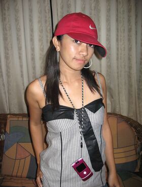 Young Pinay girl in a Nike baseball cap takes off her clothing on a loveseat