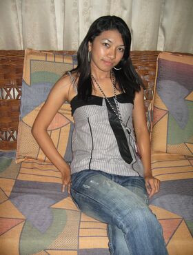 Young Pinay girl in a Nike baseball cap takes off her clothing on a loveseat