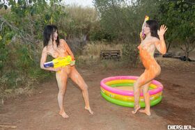 Latina lesbians Nerea Falco & Liz Rainbow have naked outdoor paintball fun